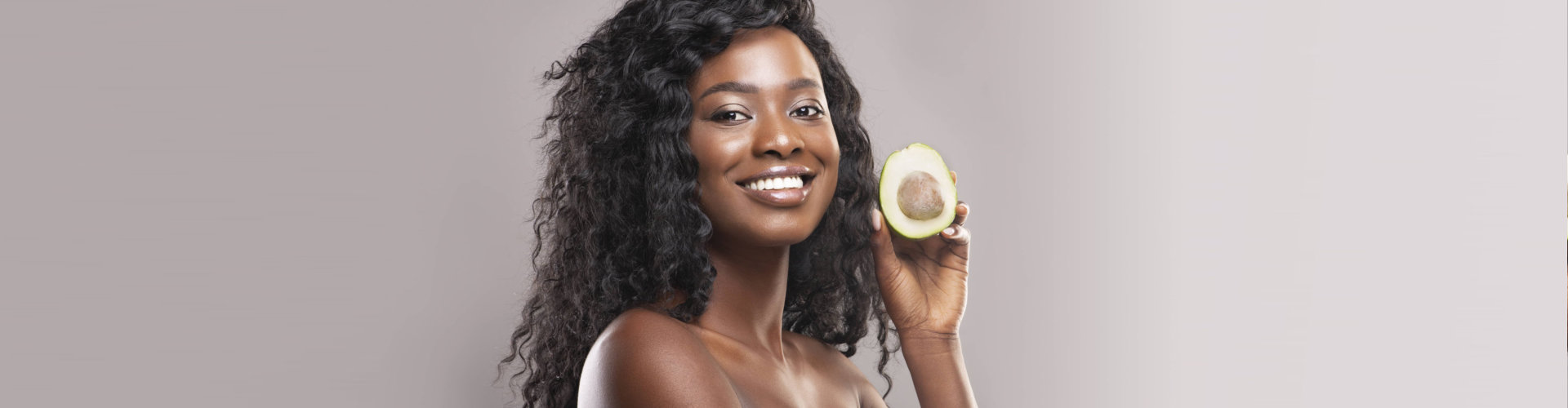 a woman smiling holding an avocado